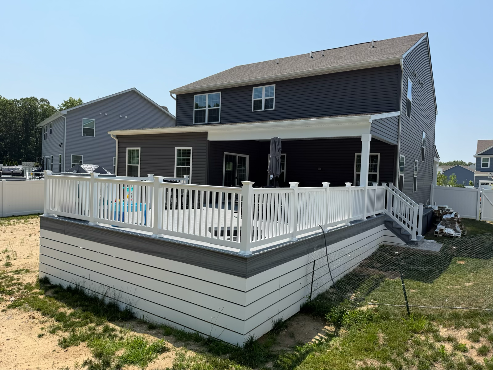 Backyard deck with white railing and pool view by Dynamic Remodeling