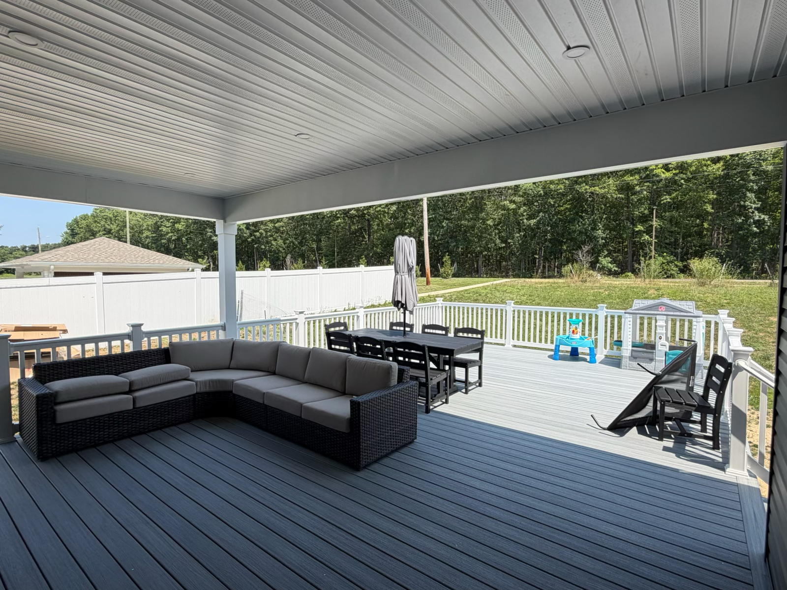 Covered composite deck with outdoor lounge furniture by Dynamic Remodeling